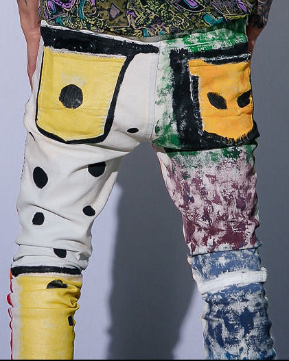 Person wearing a patterned shirt and colorful pants against a plain background