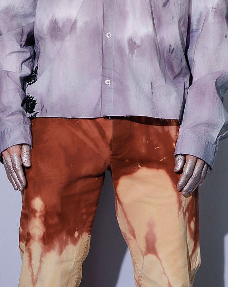 Person wearing a tie-dye shirt and pants against a plain background