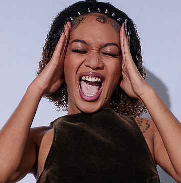 Woman in a brown dress with ruffled layers against a light blue background