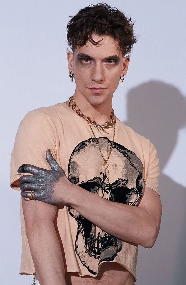 Person wearing a beige t-shirt with a graphic design and blue jeans against a light gray background