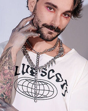 Person wearing a white t-shirt with a graphic design and colorful pants against a light gray background