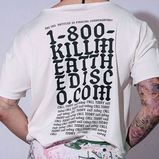 Person wearing a white t-shirt with text and colorful pants against a gray background