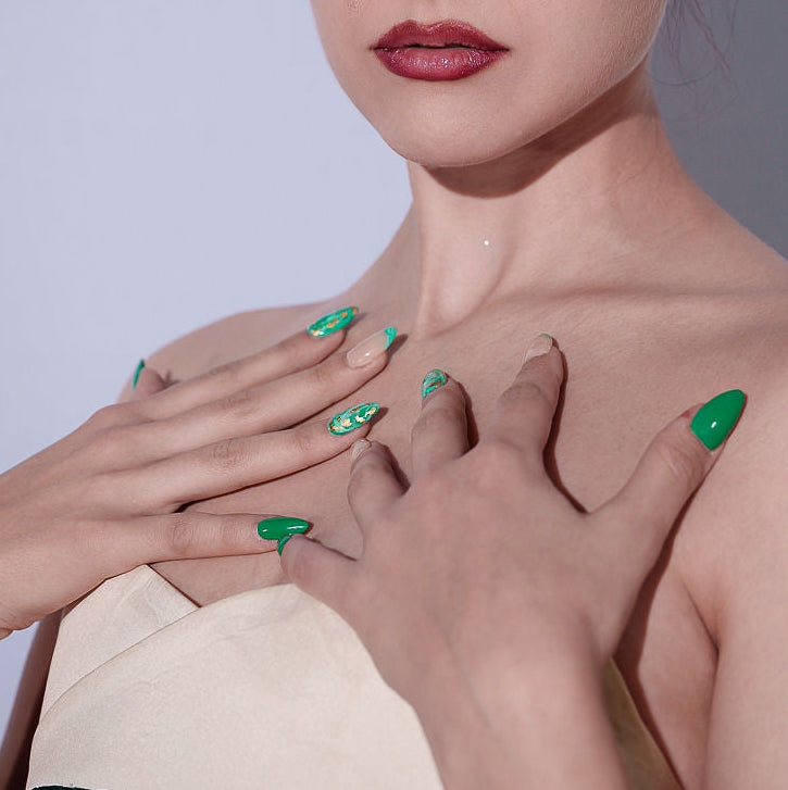 Woman with green nail polish posing against a plain background