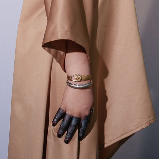 Person wearing a beige trench coat against a plain background