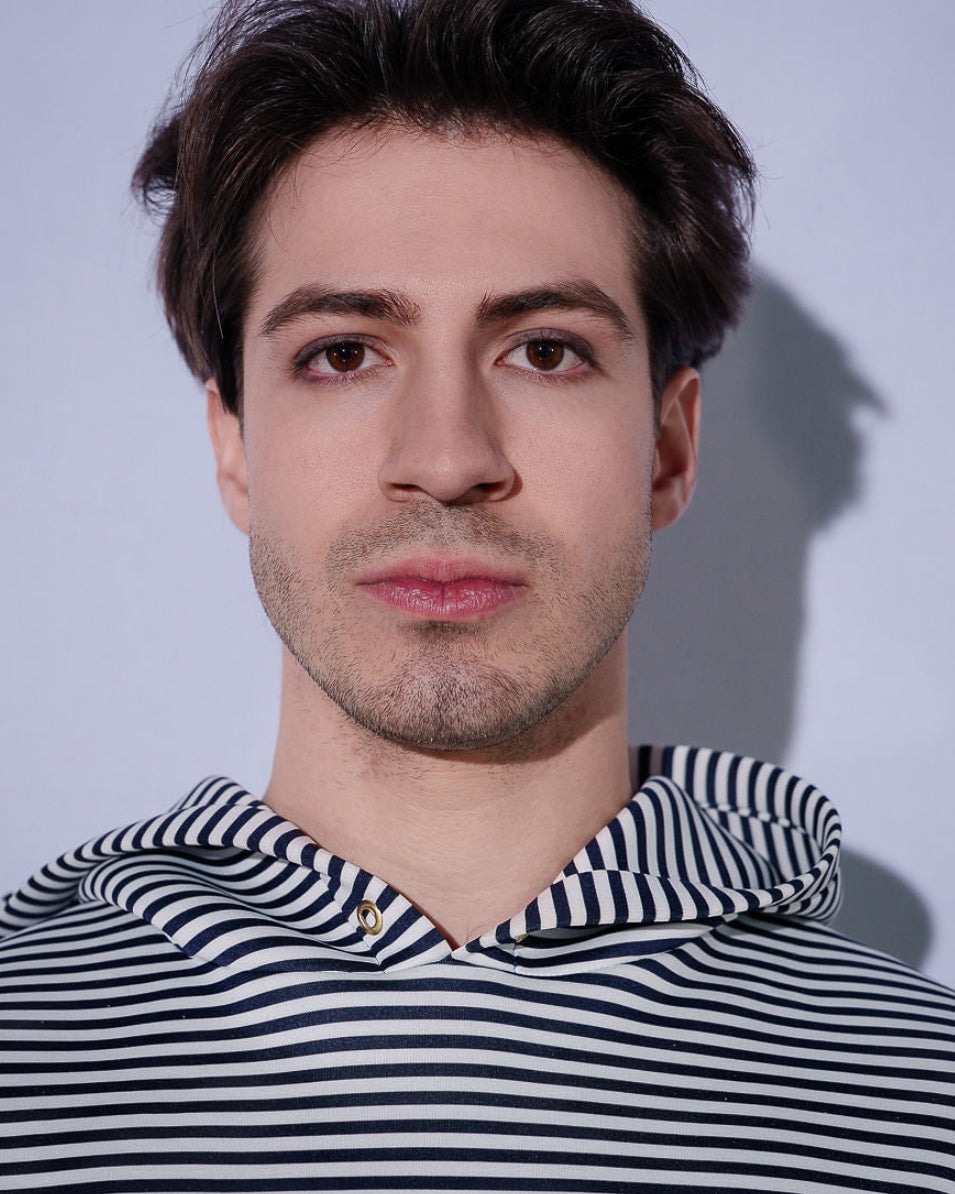 Man wearing a black and white striped hoodie against a plain background
