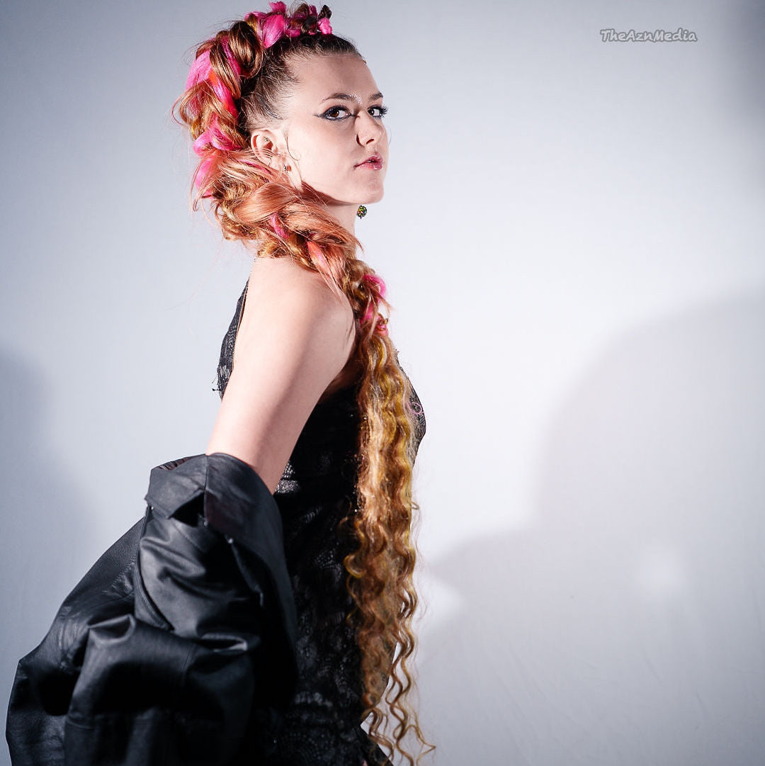 Woman with styled hair and black outfit against a gray background