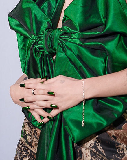 Woman wearing a green one-shoulder dress with a camouflage pattern underneath, against a plain background.